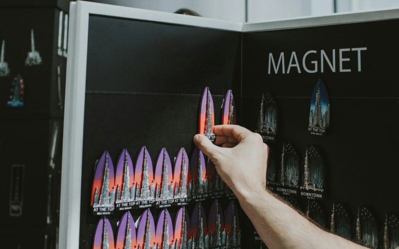 a person holding a book in front of a display of magnets